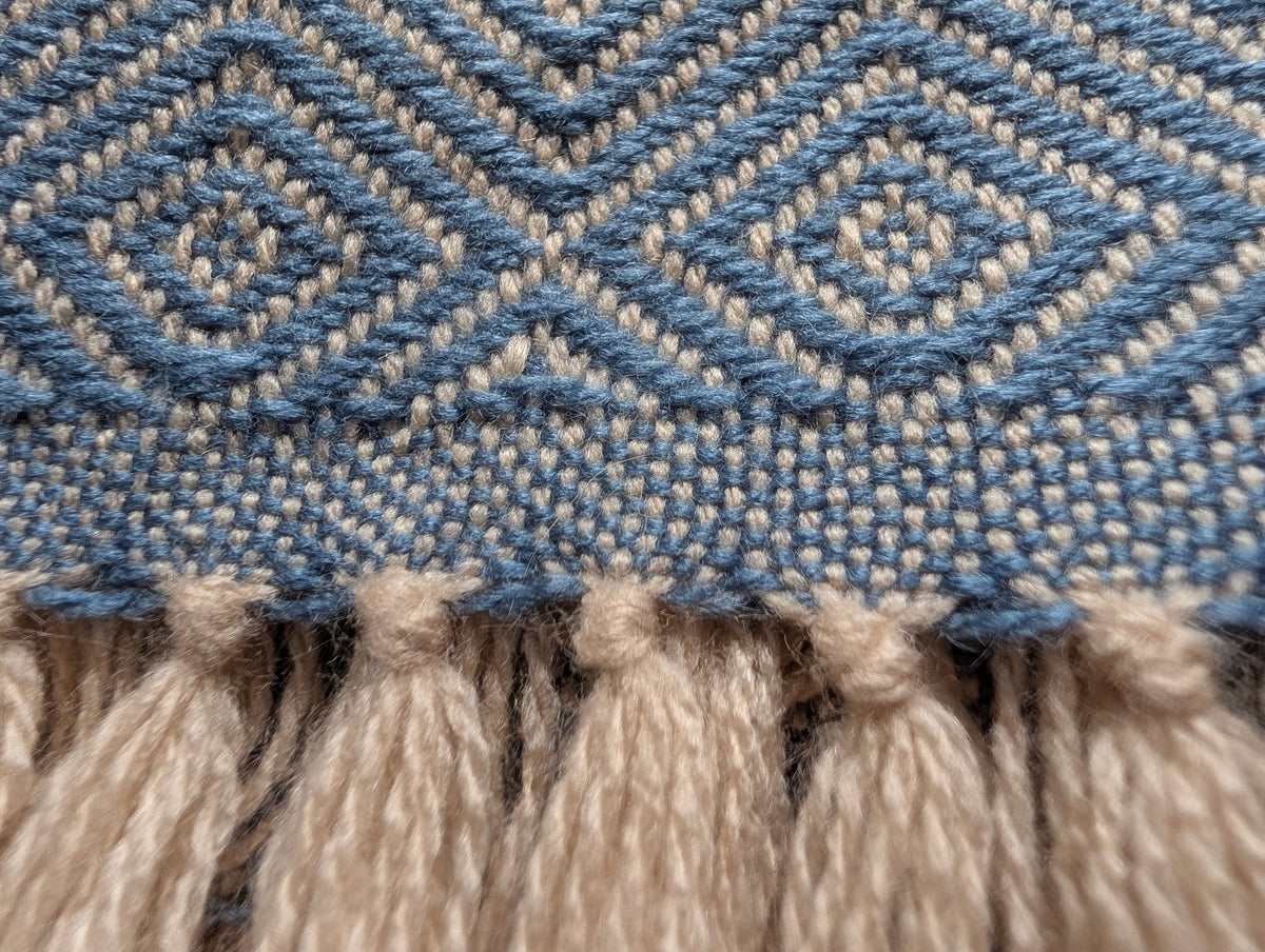 Close-up detail of hand-woven alpaca diamond blanket showing tight weave quality